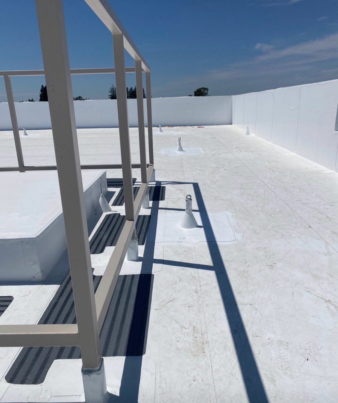 Guardrail posts and equipment supports on a coated roof